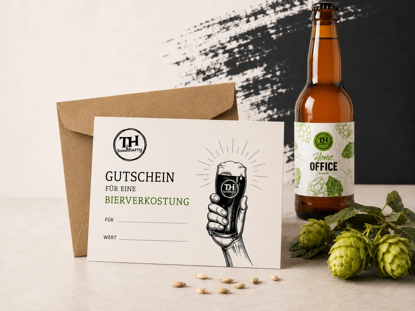 Bierverkostungs-Gutschein mit Umschlag, Bierflasche und Hopfen auf einem hellen Tisch